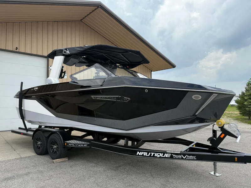 Slide: The Image of 2025 Nautique Super Air Nautique G23 boat on trailer, parked near a building. - 19