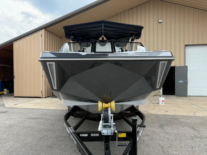 Slide: The Image of 2025 Nautique Super Air Nautique G23 boat on trailer, parked outside a garage. - 20
