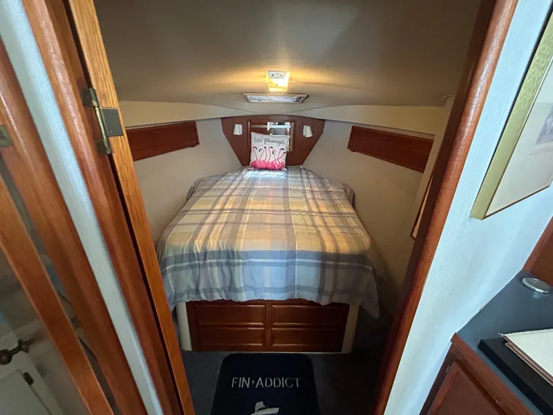 Slide: The Image of 1989 Ocean Yachts Super Sport cabin with bed, plaid bedding, and decorative pillow. - 11