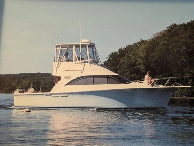 Slide: The Image of 1989 Ocean Yachts Super Sport cruising on a calm river near lush greenery. - 3