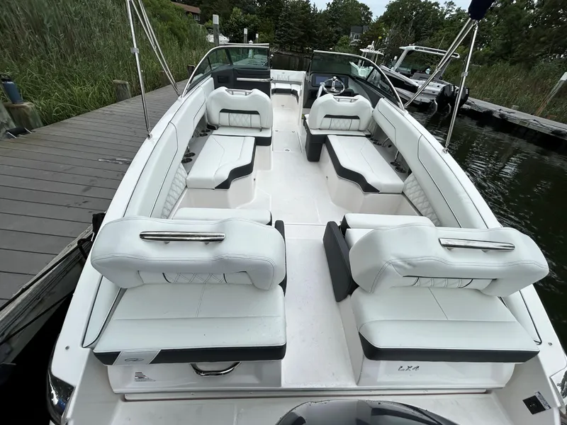 Slide: The Image of 2026 Regal LX4 boat with white seating, docked by a wooden pier. - 2