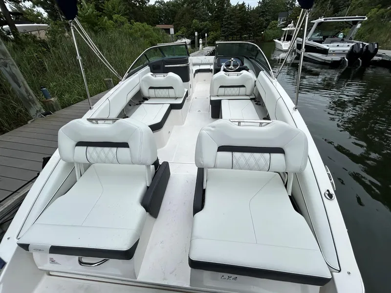 Slide: The Image of 2026 Regal LX4 boat with white seating, docked by a wooden pier, surrounded by greenery. - 3