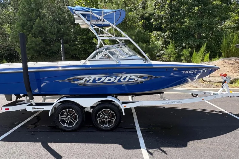 The Image of 2004 Moomba MOBIUS LS boat on trailer, blue with tower, parked outdoors. - 0