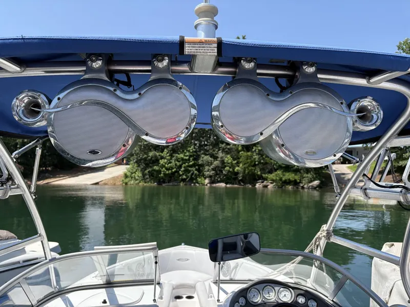 Slide: The Image of 2004 Moomba MOMBIUS LS boat with dual speakers and blue canopy on a calm lake. - 11