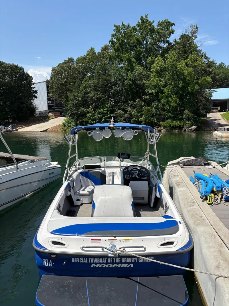 Slide: The Image of 2004 Moomba MOMBIUS LS boat docked on a sunny day, surrounded by trees and water. - 14