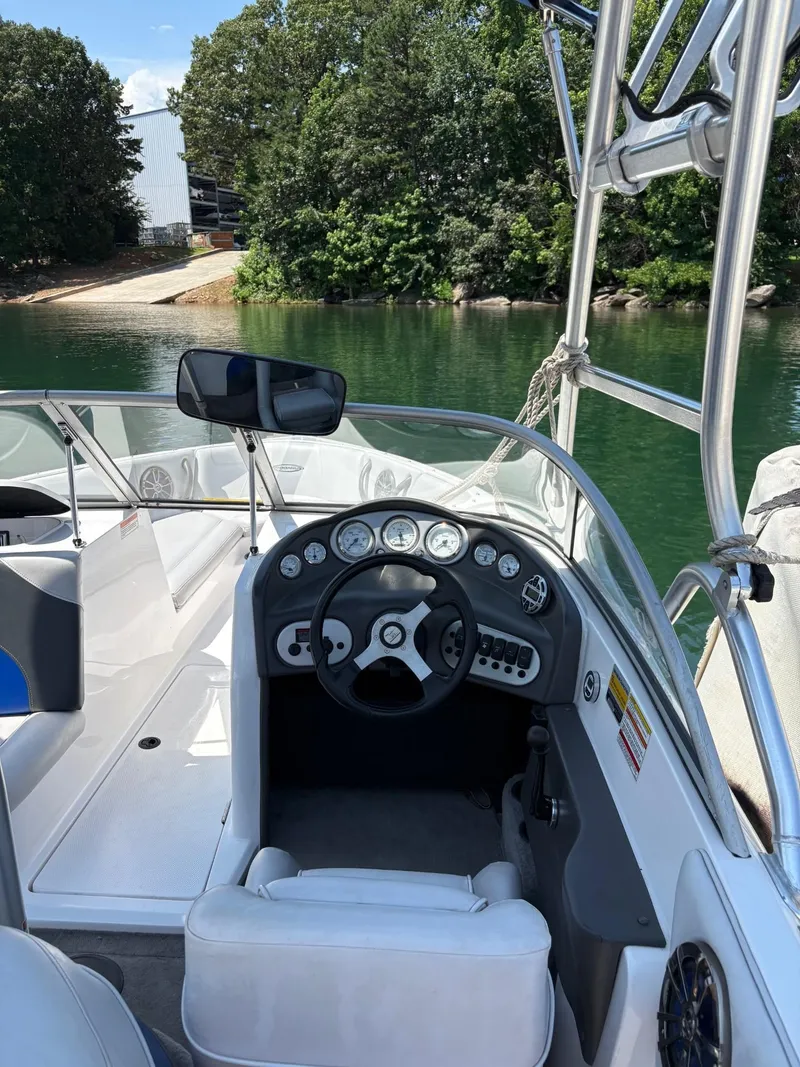 Slide: The Image of 2004 Moomba MOMBIUS LS boat interior with steering wheel and dashboard, docked by a green lake. - 15