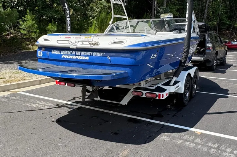 Slide: The Image of 2004 Moomba MOBIUS LS boat on trailer in parking lot, blue and white design. - 2