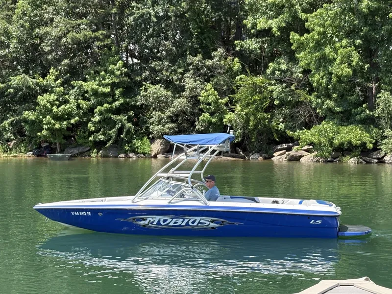 Slide: The Image of 2004 Moomba MOBIUS LS boat on a calm lake with lush green trees. - 3