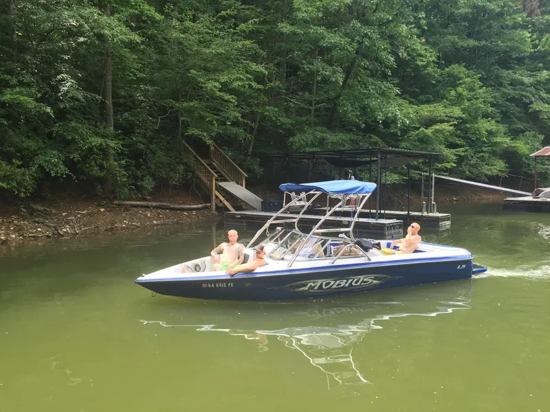Slide: The Image of 2004 Moomba MOBIUS LS boat on a lake with people, surrounded by lush greenery. - 5