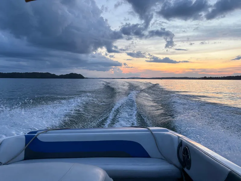Slide: The Image of 2004 Moomba MOMBIUS LS boat cruising on a lake at sunset, leaving a wake trail. - 6
