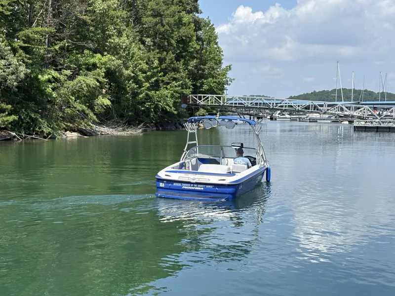 Slide: The Image of 2004 Moomba MOMBIUS LS boat cruising on a serene lake with lush greenery. - 8