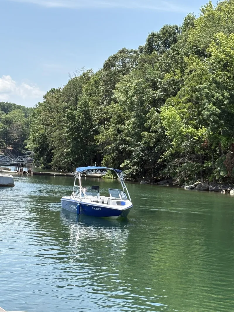 Slide: The Image of 2004 Moomba MOMBIUS LS boat cruising on a serene lake surrounded by lush trees. - 9