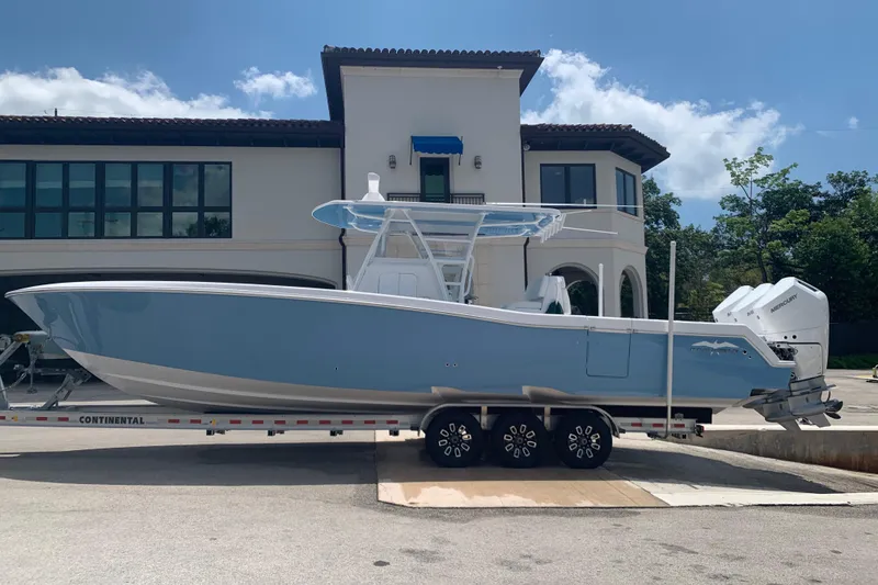 Slide: The Image of 2023 Invincible 36 Open Fisherman boat on trailer, parked in front of a modern house. - 13