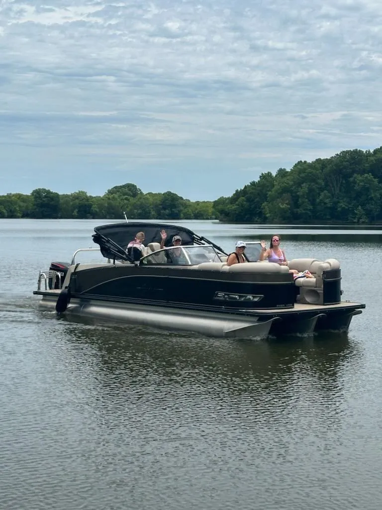 The Image of 2023 Avalon Catalina 2585 VRBW pontoon boat on a serene lake with passengers. - 1