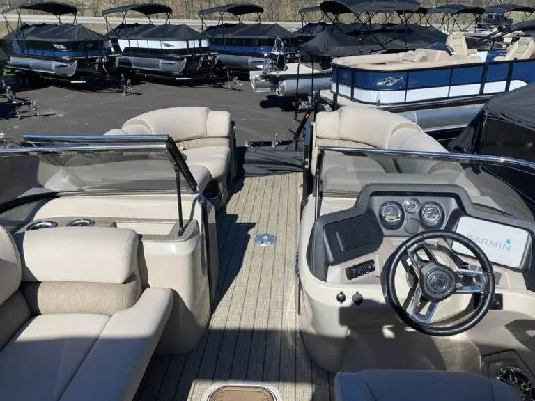 Slide: The Image of 2023 Avalon Catalina 2585 VRBW boat interior with beige seating and modern dashboard. - 3