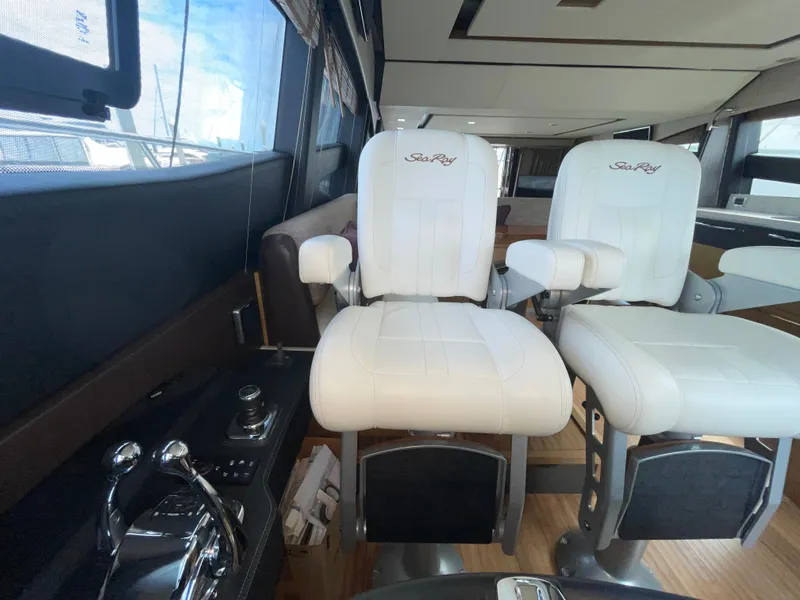 Slide: The Image of Interior of 2017 Sea Ray L590 Fly yacht with white captain chairs and control panel. - 18