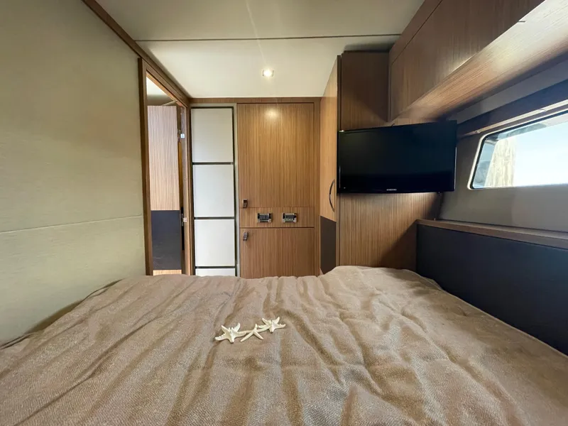 Slide: The Image of Luxurious 2017 Sea Ray L590 Fly cabin interior with bed, TV, and wooden accents. - 33