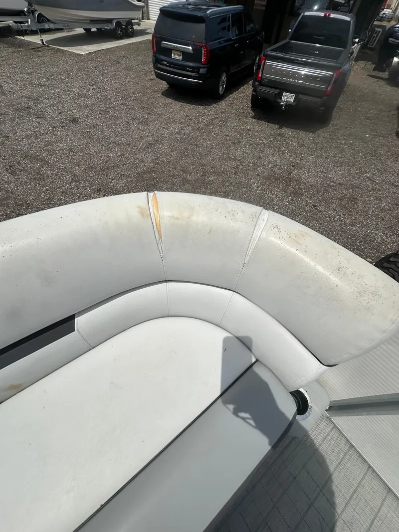 Slide: The Image of 2021 Godfrey SWEETWATER 2186 SB boat interior with white seating, parked near vehicles. - 16