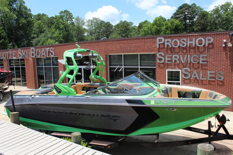 Slide: The Image of 2017 Nautique Super Air G23 boat in front of a pro shop, green and black design. - 16