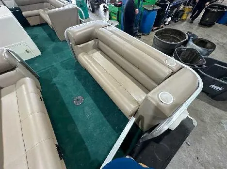 Slide: The Image of 2003 Odyssey Pontoons 2302 with beige seating and green carpet in a workshop setting. - 2