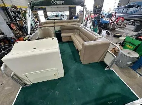 Slide: The Image of 2003 Odyssey Pontoons 2302 interior with beige seating and green carpet in a workshop. - 4