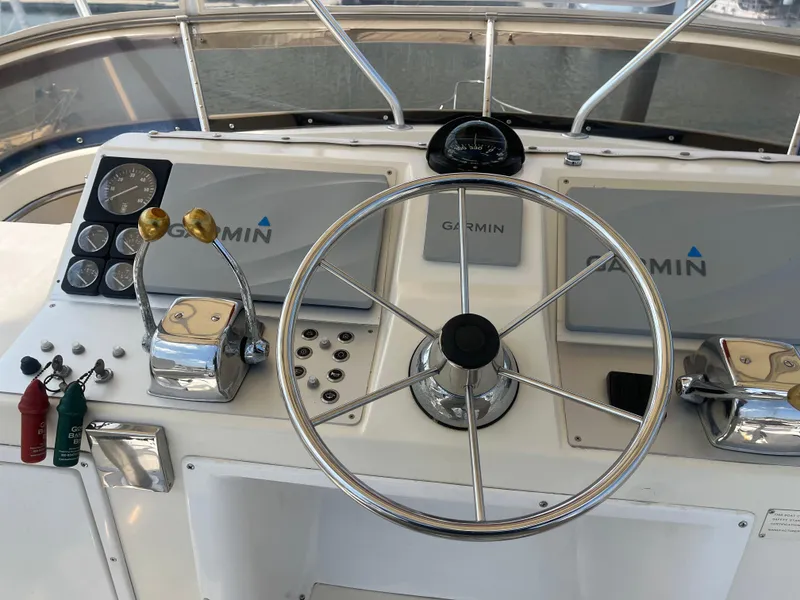 Slide: The Image of 1987 Tiara Yachts 3600 helm with Garmin navigation, steering wheel, and control levers. - 17