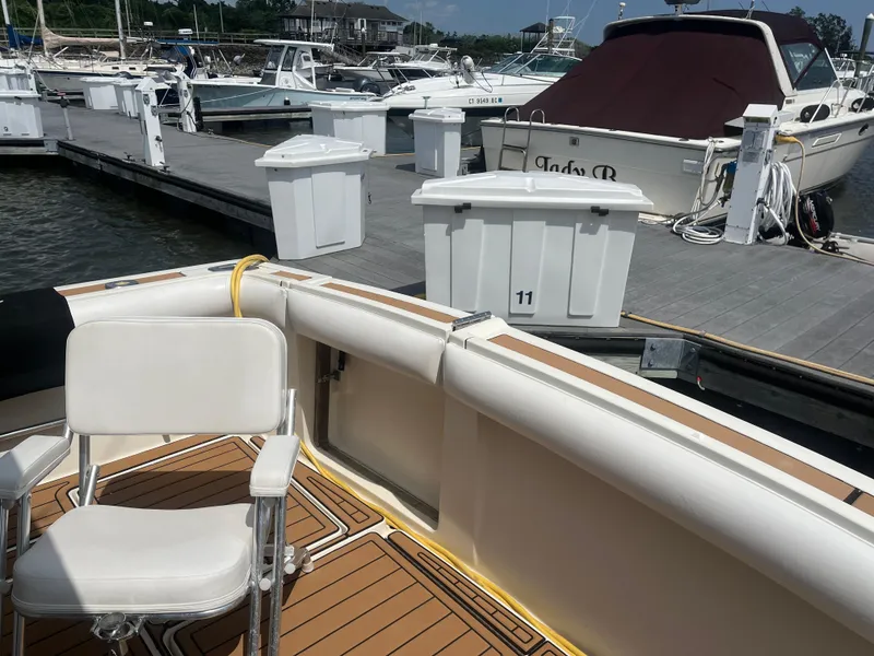 Slide: The Image of 1987 Tiara Yachts 3600 at marina, featuring white seating and wooden deck. - 19