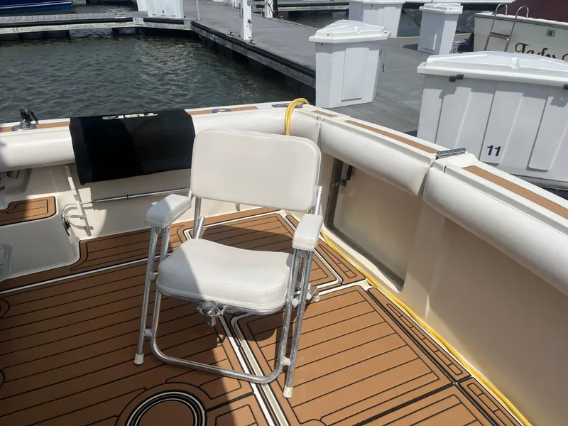 Slide: The Image of 1987 Tiara Yachts 3600 deck with white chair and teak flooring at marina. - 20