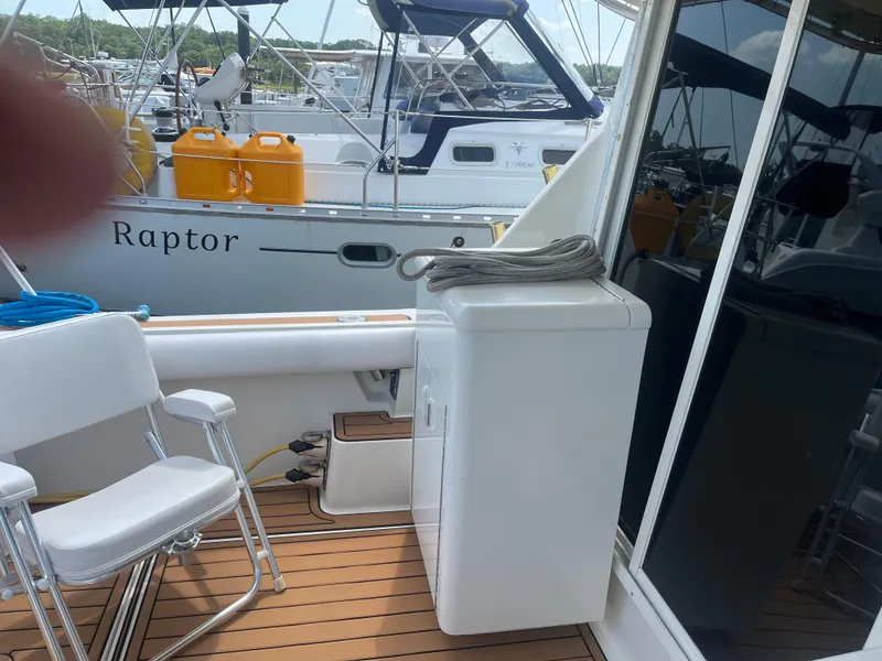 Slide: The Image of 1987 Tiara Yachts 3600 deck with chair and storage, docked near another boat. - 22