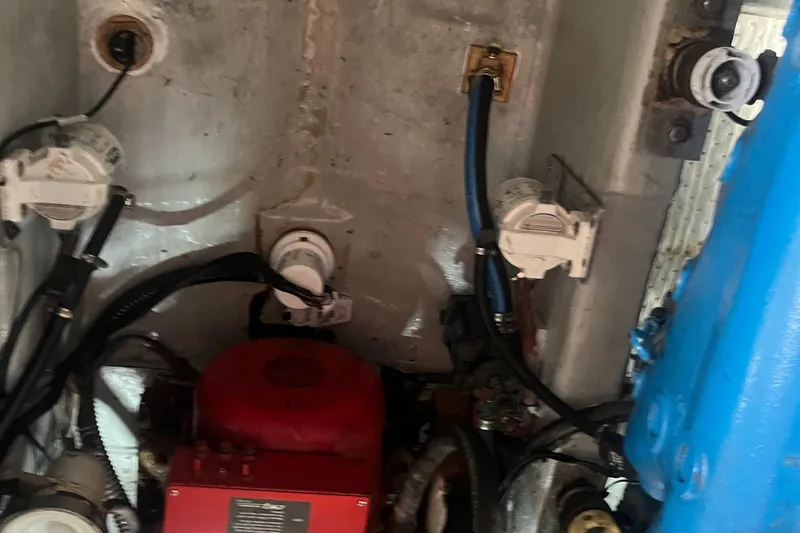 Slide: The Image of Engine compartment of a 1987 Tiara Yachts 3600, featuring various mechanical components and wiring. - 47