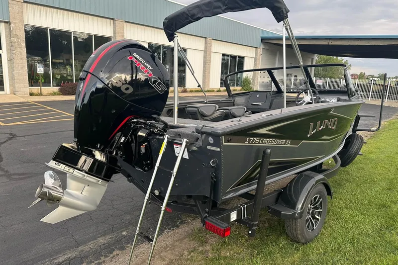 Slide: The Image of 2026 Lund 1775 Crossover XS boat with Mercury engine, parked outdoors. - 2