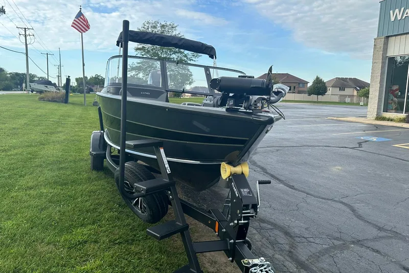 Slide: The Image of 2026 Lund 1775 Crossover XS boat on trailer, parked near a grassy area. - 5