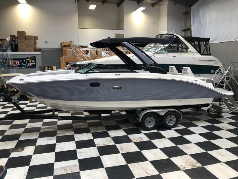 The Image of 2025 Sea Ray SDX 290 boat on display in a showroom with checkered flooring. - 0