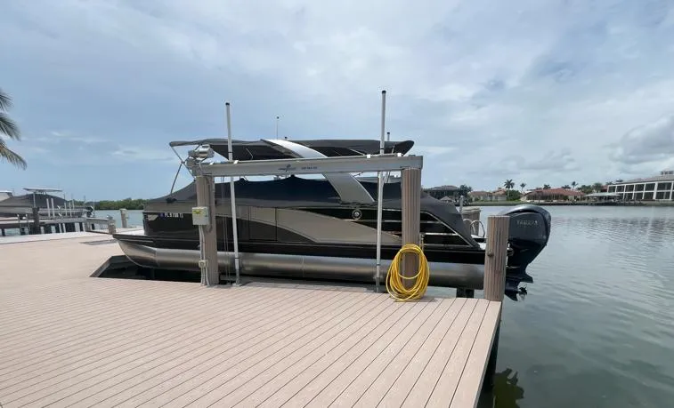 Slide: The Image of 2022 Bennington RX 25 RXFBA pontoon boat docked by a serene waterfront. - 0