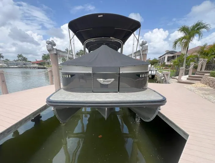 Slide: The Image of 2022 Bennington RX 25 RXFBA pontoon boat docked, covered, with tropical background. - 3