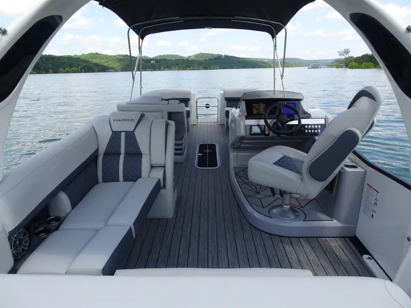 Slide: The Image of 2025 Harris Grand Mariner 250 boat interior with luxurious seating and modern helm on a scenic lake. - 12