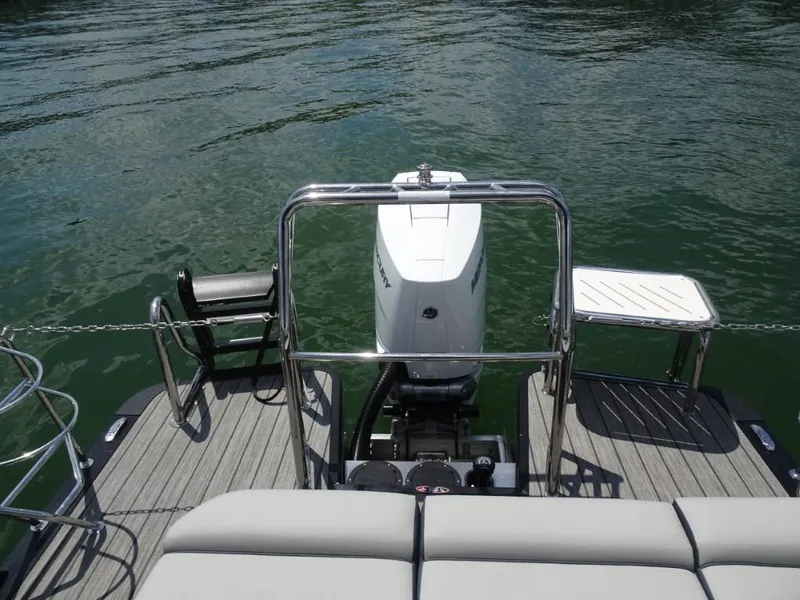 Slide: The Image of 2025 Harris Grand Mariner 250 boat stern with motor and seating, on calm water. - 26