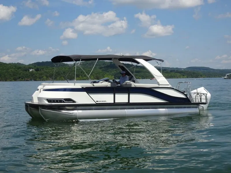 Slide: The Image of 2025 Harris Grand Mariner 250 pontoon boat on a scenic lake under a blue sky. - 7