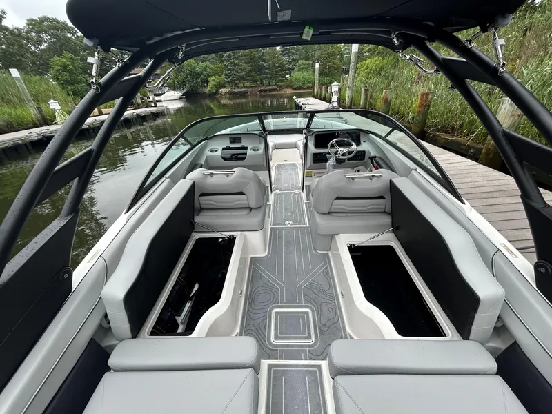 Slide: The Image of 2026 Regal LX2 boat interior with sleek seating and modern dashboard, docked by lush greenery. - 6