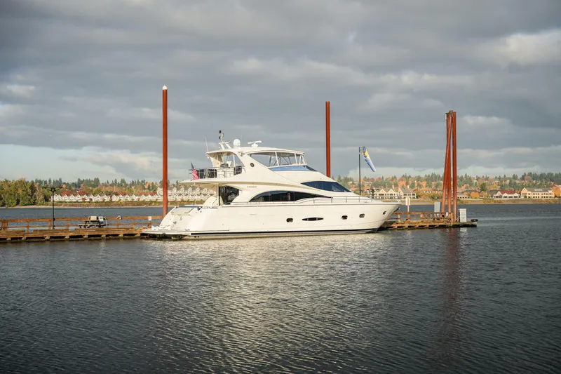 The Image of Luxury 2006 Marquis 65 yacht docked on a serene waterfront under cloudy skies. - 0