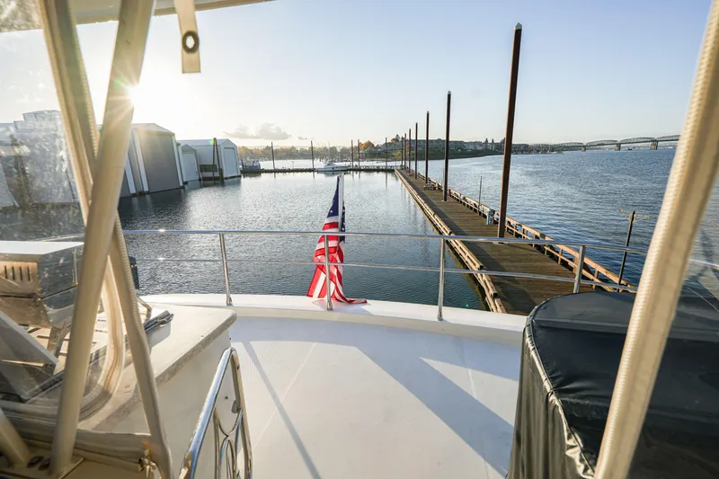 Slide: The Image of 2006 Marquis 65 yacht docked at marina with American flag, sunny waterfront view. - 34