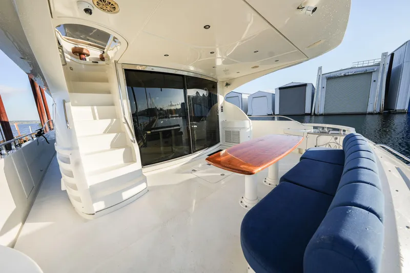 Slide: The Image of Luxurious 2006 Marquis 65 yacht deck with blue seating, wooden table, and spiral staircase. - 4