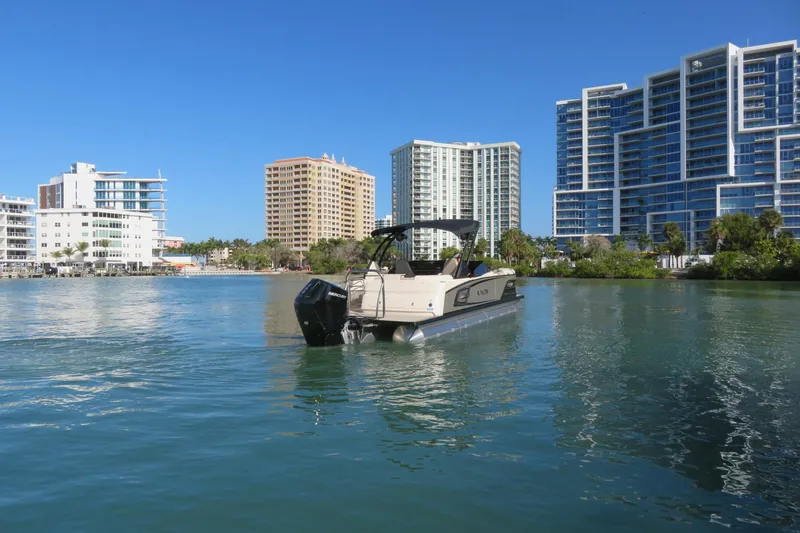 Slide: The Image of 2026 Avalon Excalibur LTD 25’ Tritoon on water, city skyline in background. - 100