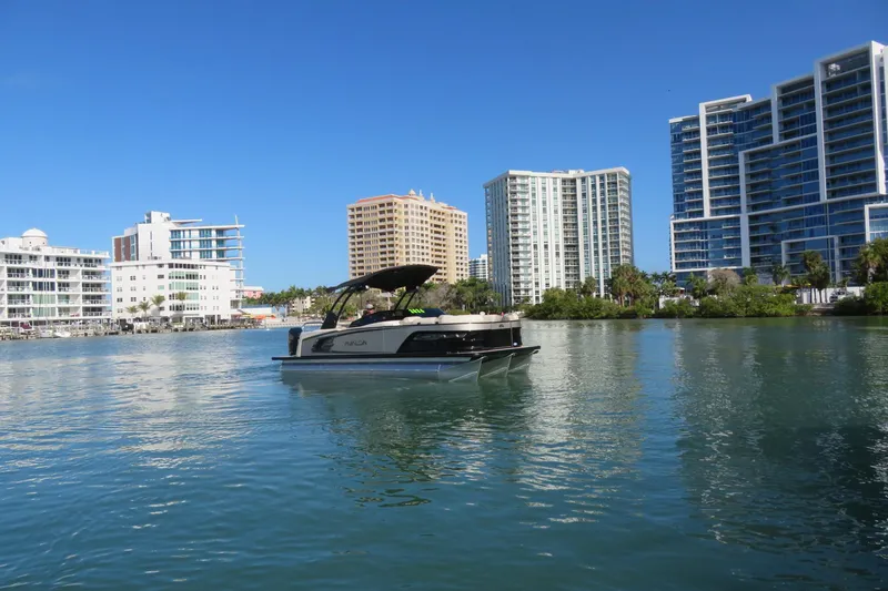 Slide: The Image of 2026 Avalon Excalibur LTD 25’ tritoon on water, city skyline in background. - 95