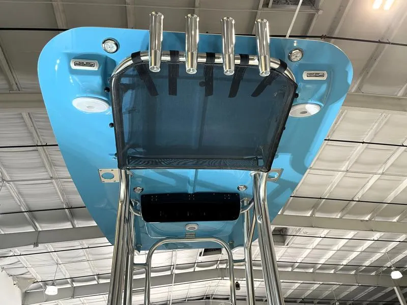 Slide: The Image of 2025 Key West 210 Bay Reef boat's blue T-top with rod holders in a warehouse. - 10