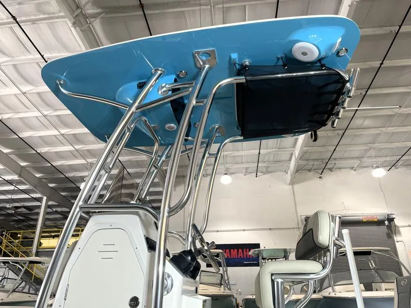 Slide: The Image of 2025 Key West 210 Bay Reef boat with blue T-top and stainless steel frame in a warehouse. - 8