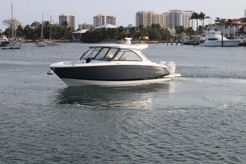 Slide: The Image of 2022 Regal LX36 boat cruising in a marina with city skyline background. - 10