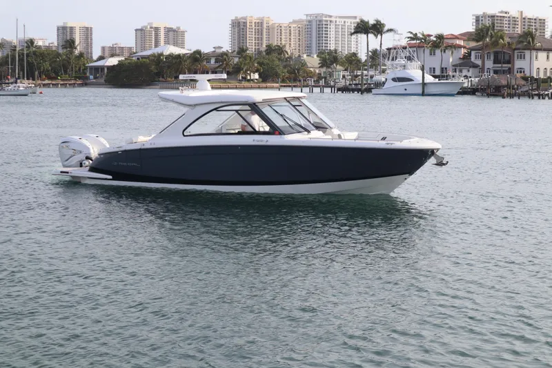 Slide: The Image of 2022 Regal LX36 boat on calm water near waterfront buildings. - 14