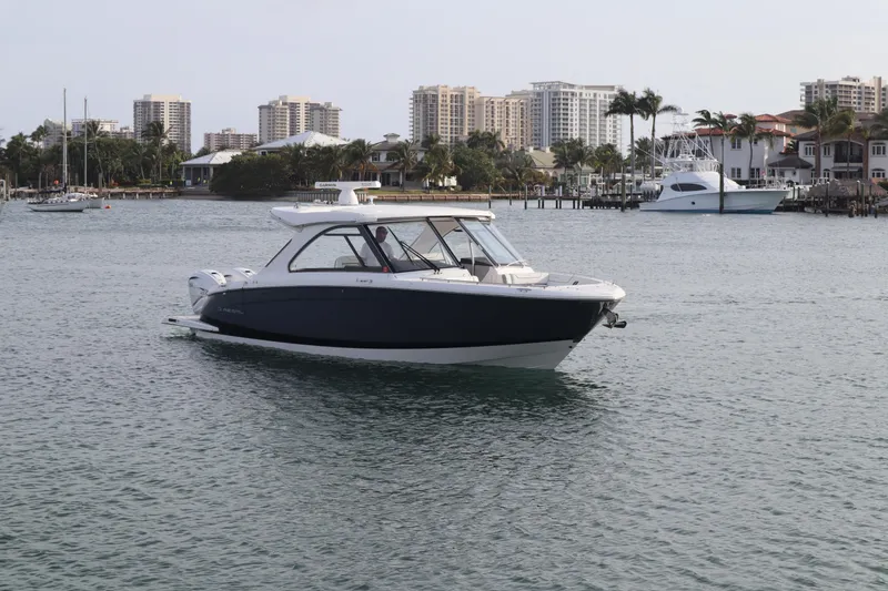 Slide: The Image of 2022 Regal LX36 boat cruising in a coastal city harbor with skyscrapers in the background. - 20