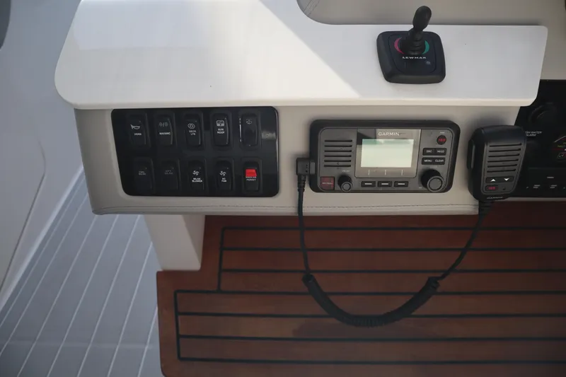 Slide: The Image of Control panel of 2022 Regal LX36 boat with radio and switches on wooden deck. - 42